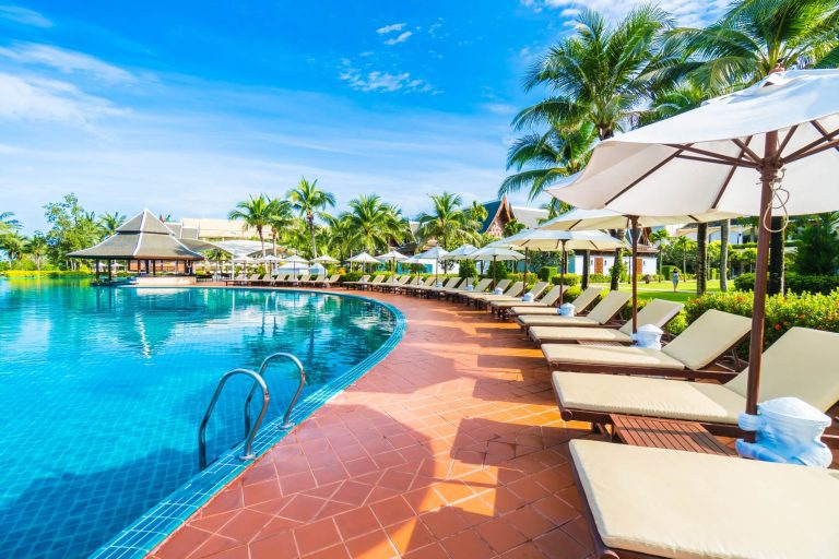 Chaises longues et parasols au bord d'une piscine dans un cadre tropical.